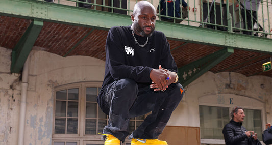 Virgil Abloh, founder of Off-White, stands in front of his iconic diagonal-striped artwork